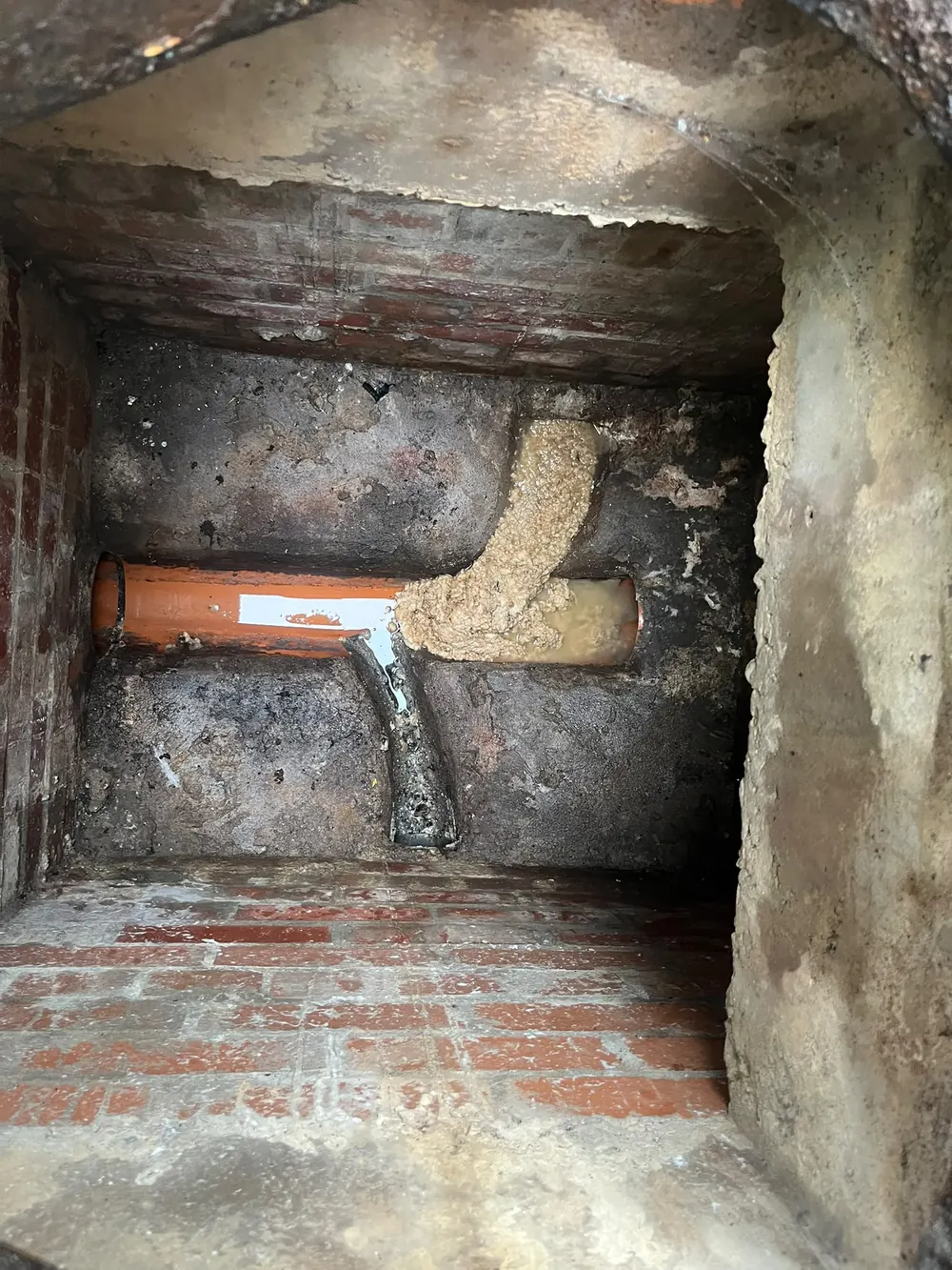 Damaged drainage connection exposed in a brick inspection chamber