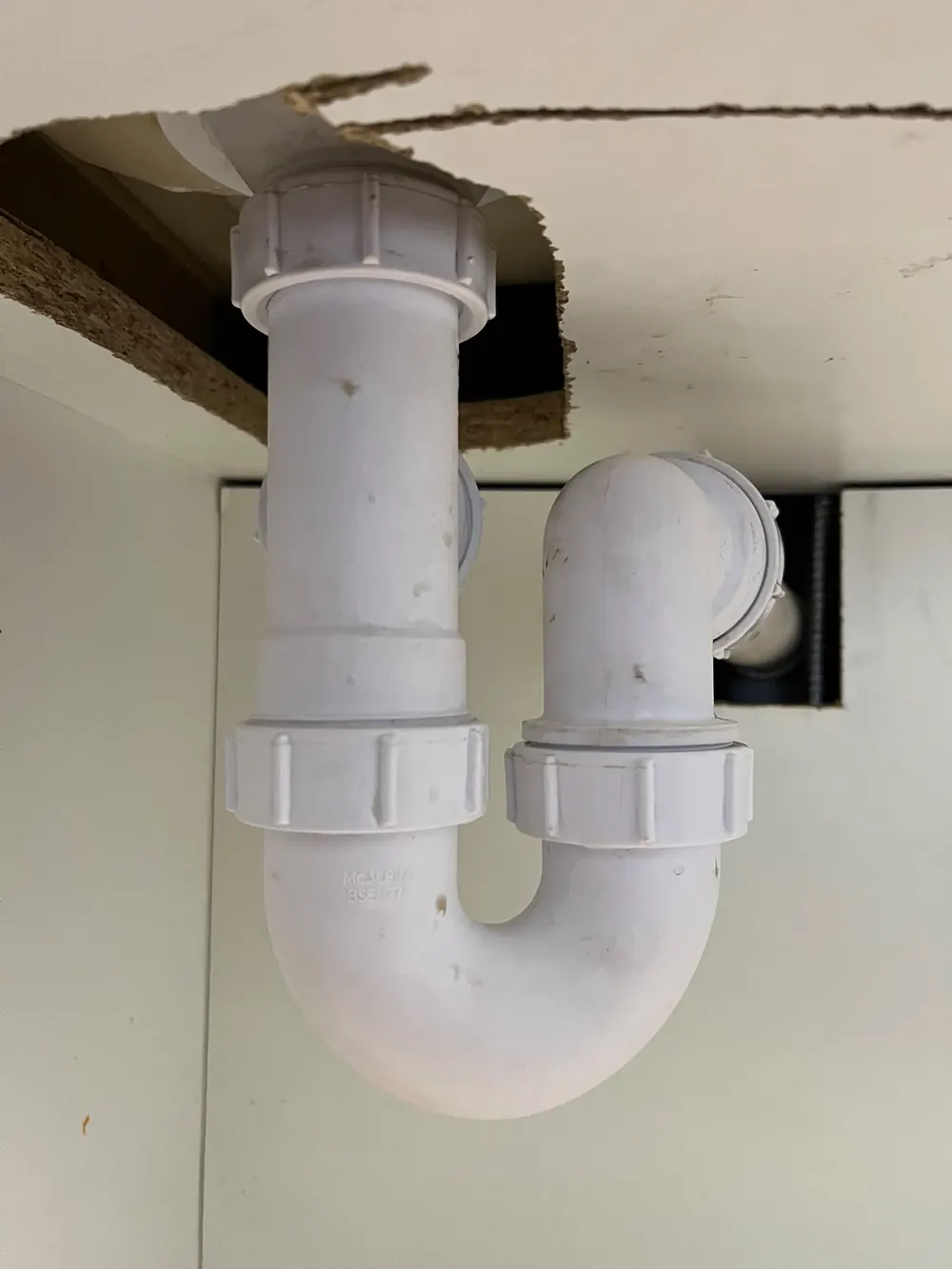 Repaired basin waste pipe beneath a sink